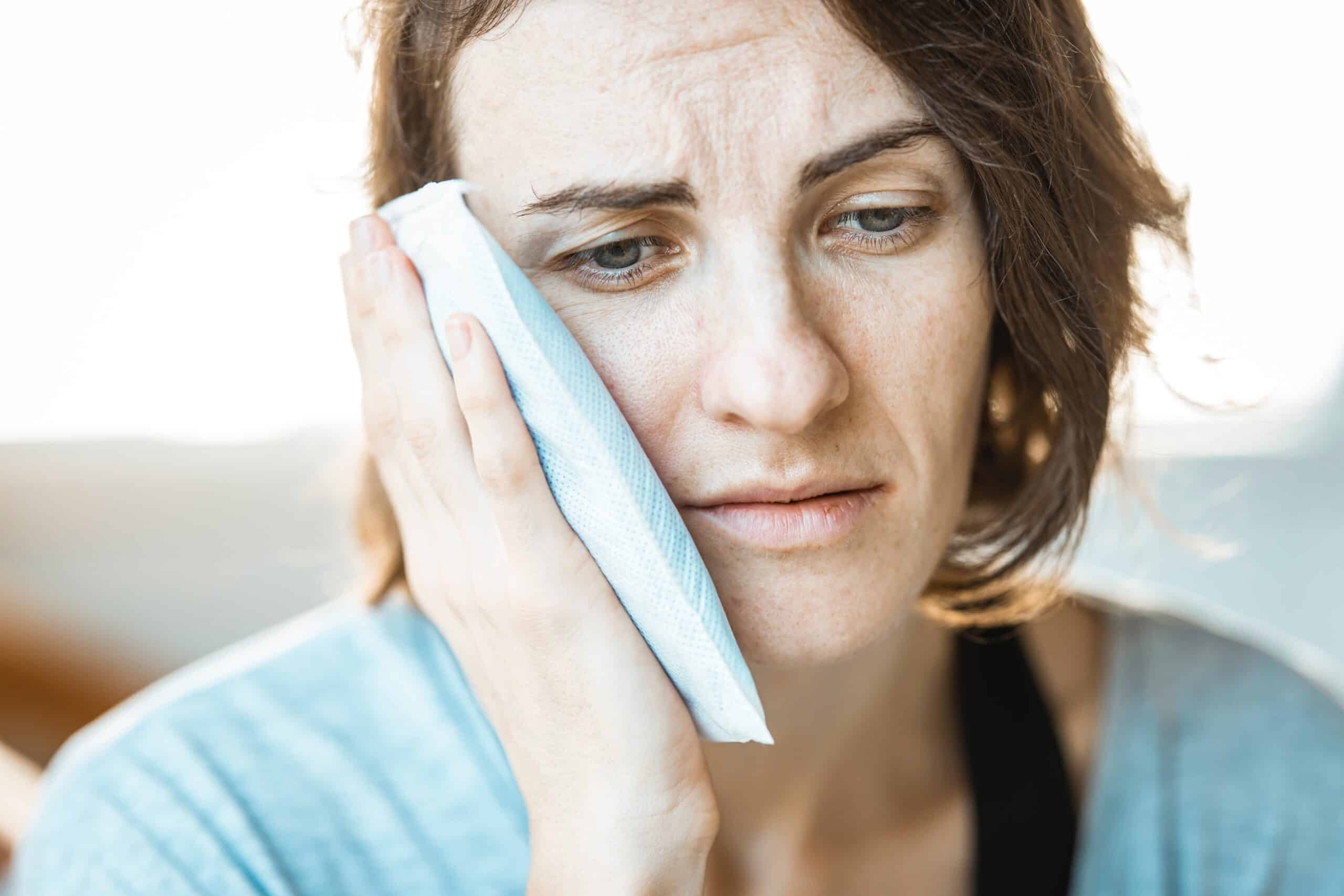 Woman holding a cold compress to her cheek for tooth pain