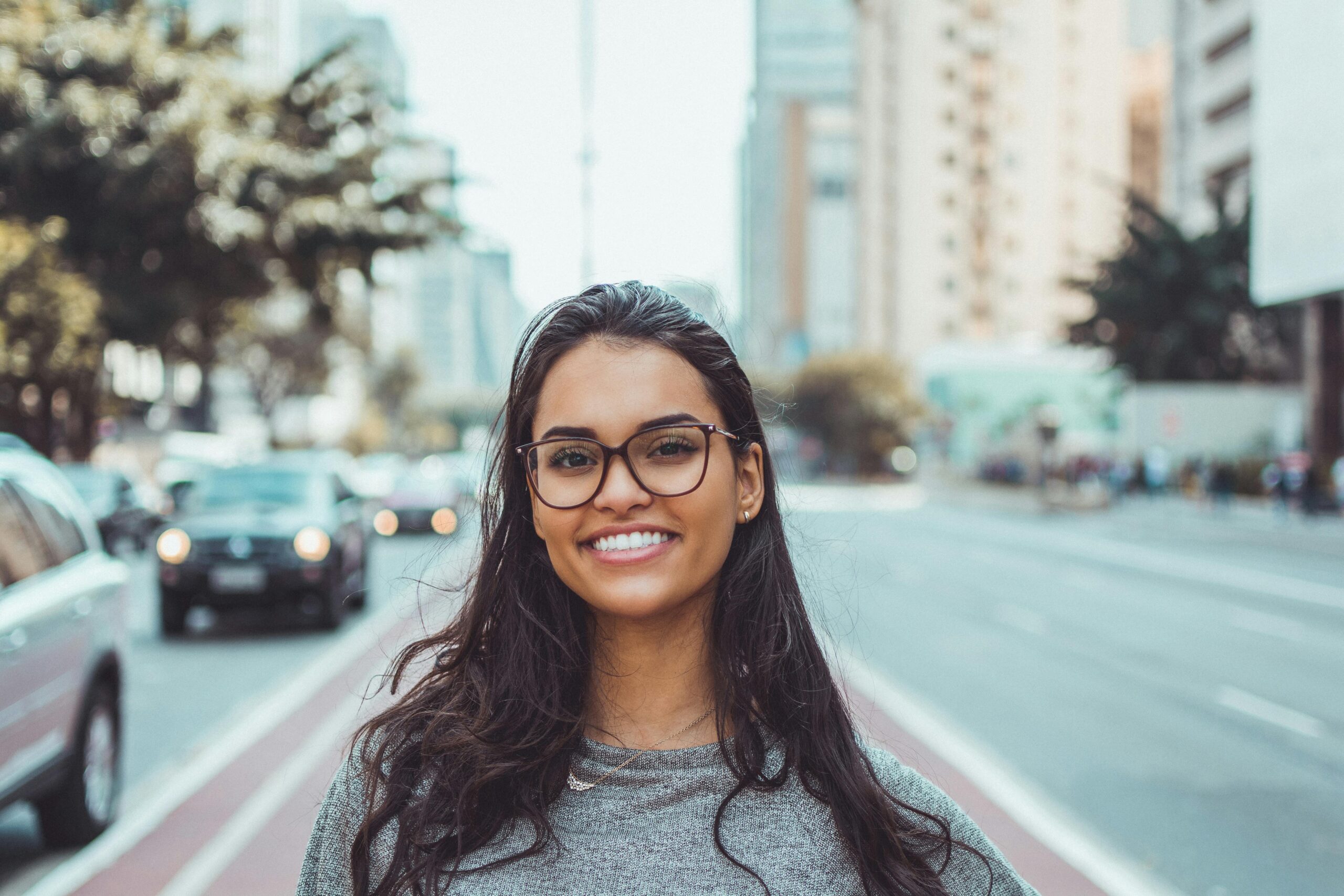 Smiling woman with glasses on a city street - Periodontist Southern Pines & Sanford NC | Van Scoyoc Periodontics & Implants Smiling woman with glasses on a city street