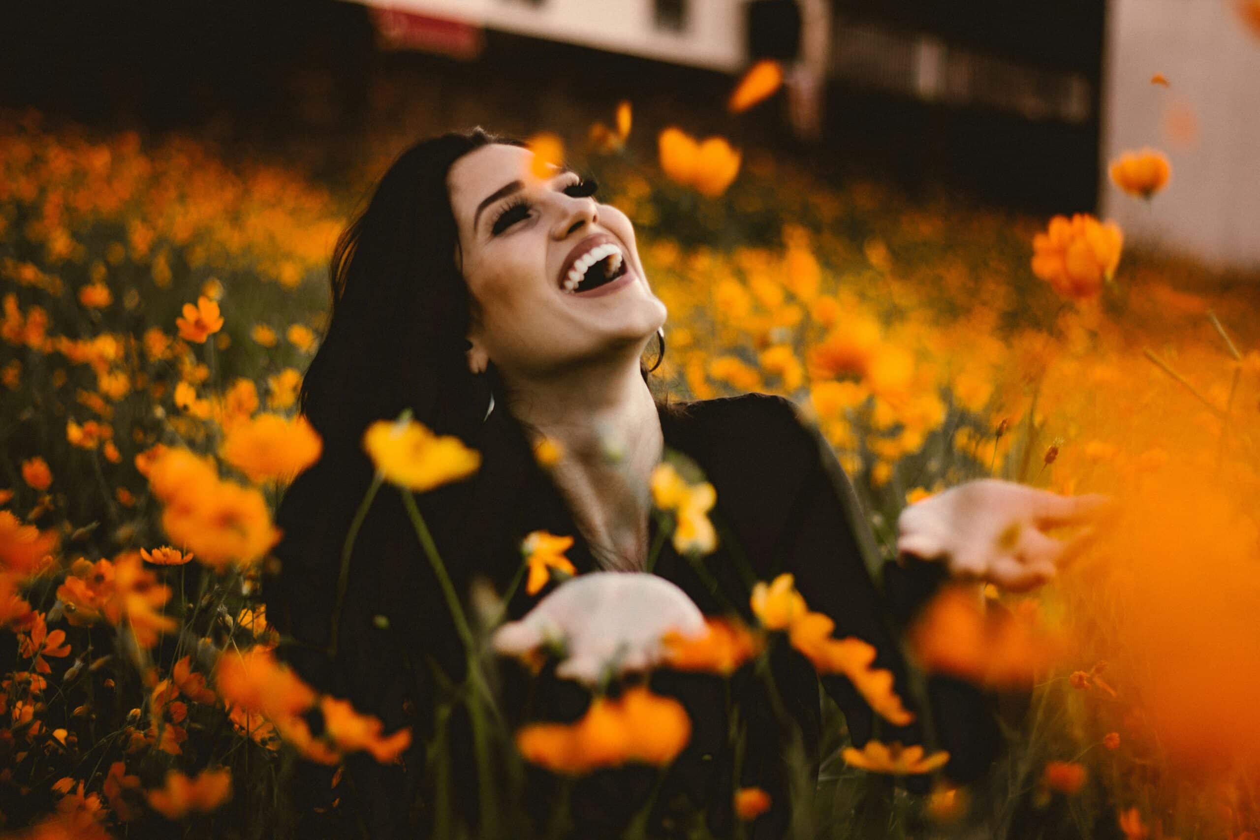 Woman laughing in a field of orange flowers - Periodontist Southern Pines & Sanford NC | Van Scoyoc Periodontics & Implants Woman laughing in a field of orange flowers